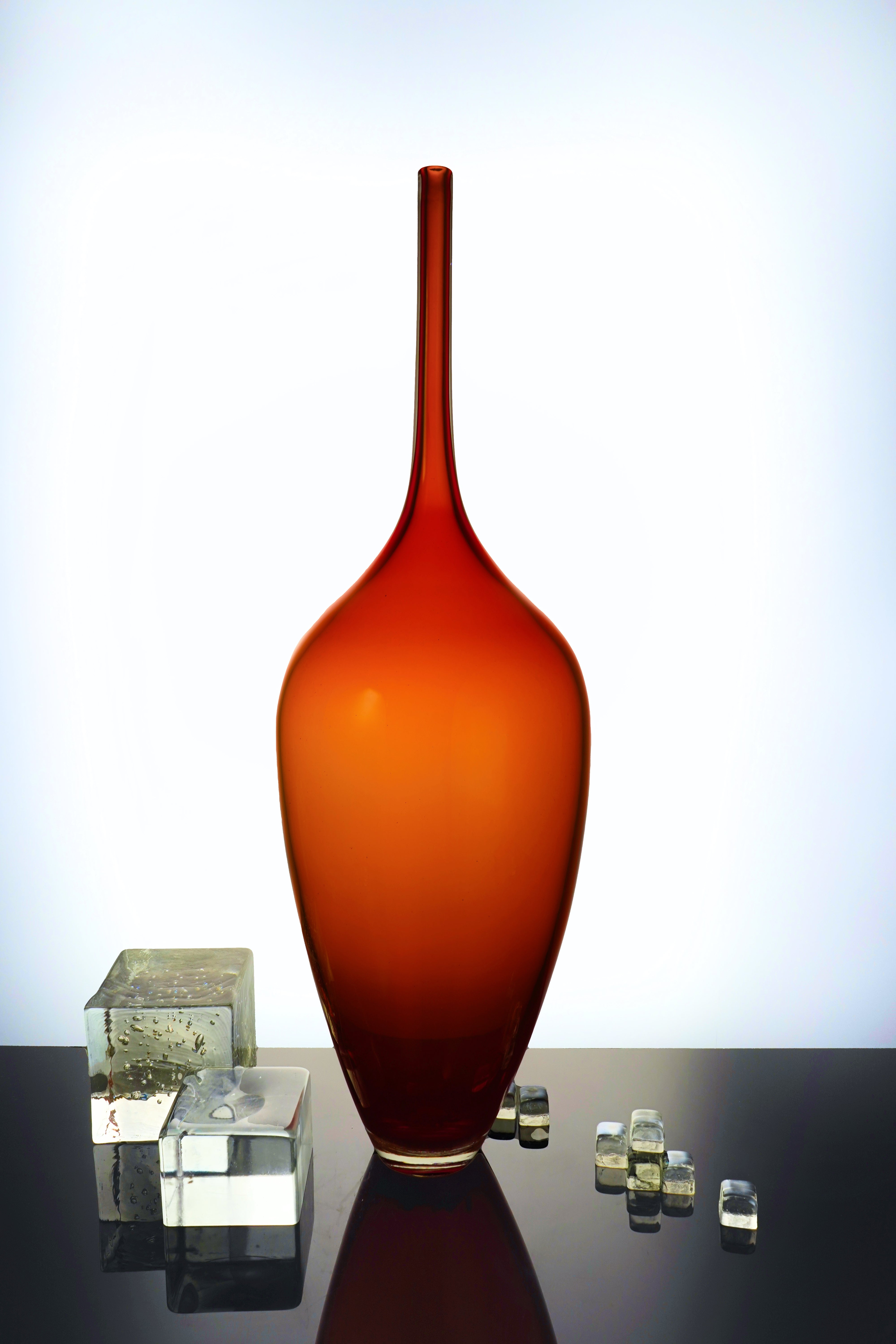 Edols & Elliott Red Glass Bottle Sculpture, handmade with exquisite craftsmanship. The vibrant red glass adds a pop of color and sophistication to any space.